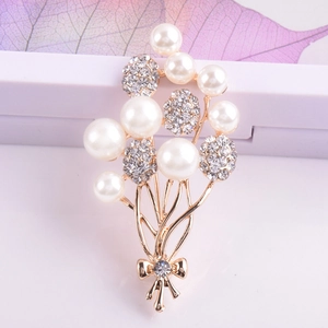 Detailaufnahme einer Brosche in Ballonform mit Perlen, Strass und goldener Schleife