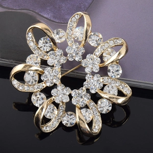 Vue rapprochée d'une broche florale dorée sertie de strass brillants et design ajouré