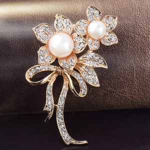 Vue macro d'une broche fleur dorée avec perles blanches et strass étincelants de luxe