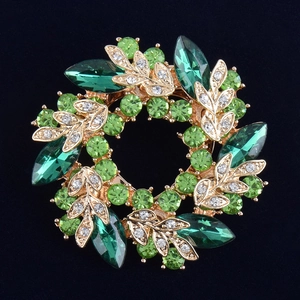 Gros plan d'une broche florale en cristal vert avec finition dorée sur velours noir