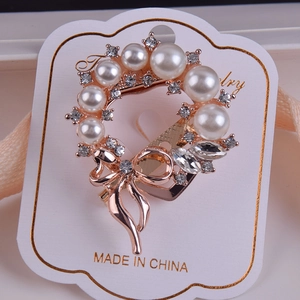Detail view of a rose gold wreath brooch with white pearls and sparkling rhinestones