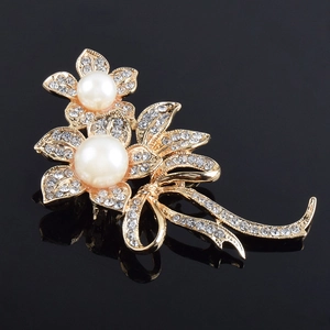 Vue détaillée d'une broche fleur dorée ornée de perles blanches et de cristaux brillants