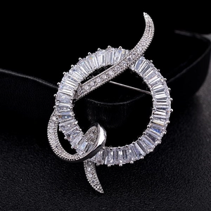 Élégante broche ruban circulaire argentée avec cristaux de zircon sur fond de cuir noir