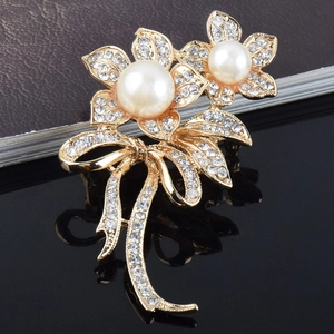 Détail macro d'une broche fleurie en cristal avec perles et ruban sur base dorée
