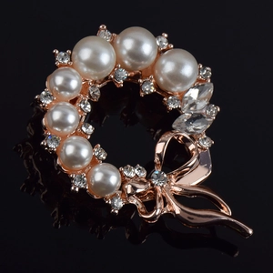 Close-up of rose gold brooch with pearls, sparkling rhinestones and a delicate bow detail