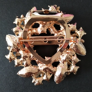 Vue détaillée du dos d'une broche fleur plaquée or avec épingle de sûreté et cristaux bleus