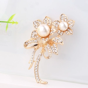 Gros plan détaillé d'une broche nœud floral doré avec perles et strass étincelants