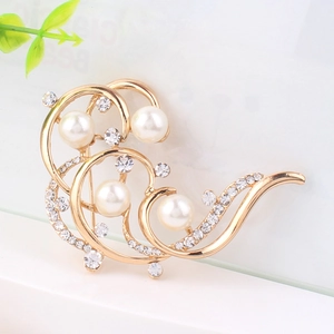 Nahaufnahme der eleganten Goldwellen-Brosche mit weißen Perlen und glänzenden Strass