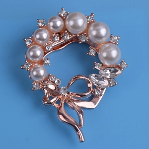 Elegant rose gold pearl brooch with sparkling rhinestones and a delicate bow detail