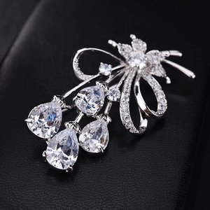 Détail d'une broche fleurie argentée avec zircons en goutte sur cuir noir