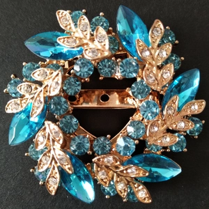 Détail macro d'une broche fleur dorée ornée de cristaux bleu clair et de strass brillants