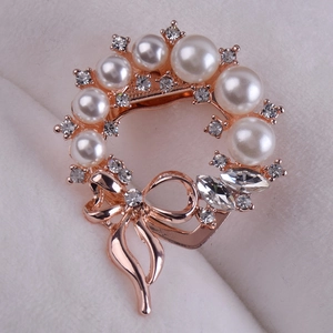 Close-up of a rose gold wreath brooch with white pearls and sparkling crystals