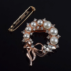 Macro detail of elegant pearl brooch with sparkling crystals and rose gold alloy bow