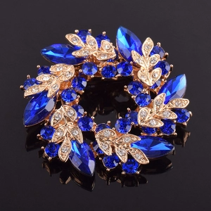 Vue détaillée d'une broche florale en cristal bleu avec des textures de feuilles dorées