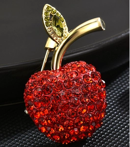 Gros plan d'une broche pomme de luxe avec cristaux rouges et feuilles dorées