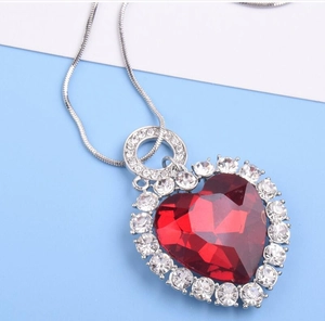 Gros plan détaillé d'un pendentif cœur en cristal rouge avec chaîne serpent argentée et brillants
