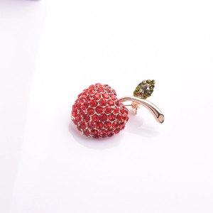 Vue détaillée de la broche pomme en cristal rouge avec feuille verte et dorée