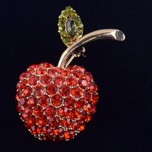 Vue macro détaillée d'une broche pomme avec des strass rouges et une feuille verte
