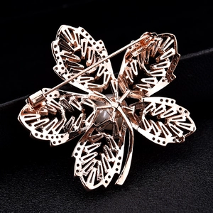 Broche fleur en or rose avec zircons, design évidé complexe et perle centrale