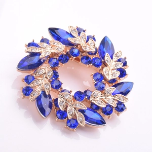Vue macro détaillée d'une broche couronne vintage avec cristaux bleu marine et feuilles d'or