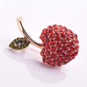 Gros plan d'une broche cerise de luxe sertie de strass rouges sur base en métal doré