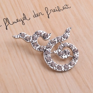 Silver crystal rhinestone brooch with fluid scroll design on a rustic wooden background