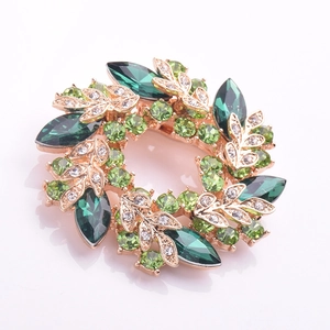 Vue détaillée d'une broche florale dorée avec cristaux verts et petits diamants blancs