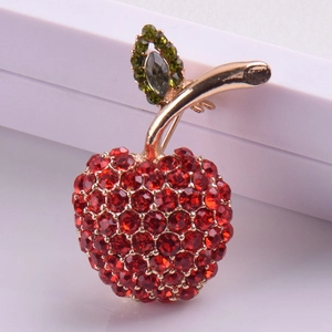 Détail d'une broche cerise ornée de strass rouges et de feuilles en cristal vert