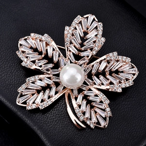 Détail macro d'une broche feuille avec perle centrale et pierres de zircone étincelantes