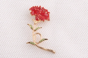 Macro view of carnation brooch with red enamel petals and green rhinestone leaves