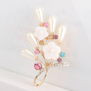 Detail einer floralen Brosche aus Gold mit weißen Muscheln, Perlen und bunten Kristallen