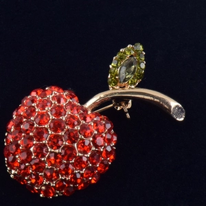 Détail macro d'une broche cerise de luxe avec strass rouges et feuille dorée