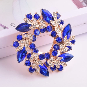 Vue macro de broche couronne avec cristaux bleu foncé et détails de feuilles dorées