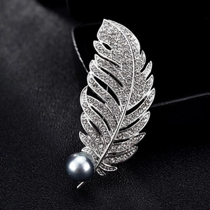 Detail of silver feather brooch with sparkling crystals and a dark grey pearl