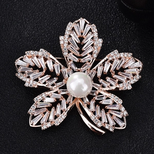 Détail d'une broche fleur à cinq pétales en or rose avec zircons et perle blanche