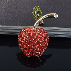 Gros plan détaillé d'une broche pomme de luxe sertie de cristaux rouges et verts