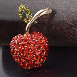 Détail macro d'une broche pomme en strass rouges avec accents de feuilles vertes