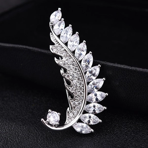 Elegant silver leaf brooch with sparkling zircon inlay over a dark textured backdrop