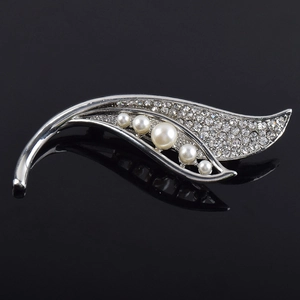 Détail macro de la broche feuille argentée avec cinq perles blanches et strass étincelants