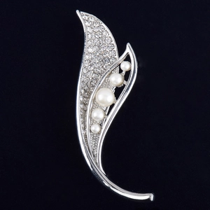 Détail de la broche feuille argentée avec strass brillants et cinq perles élégantes