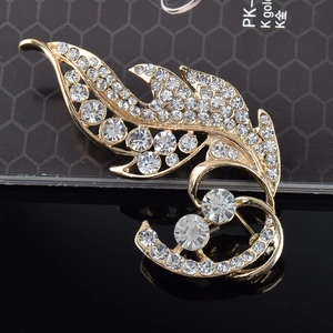 Macro d'une broche feuille dorée avec strass clairs sur une surface noire texturée