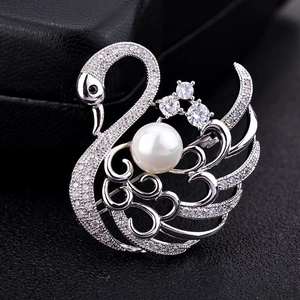 Macro shot of silver swan brooch with white zircon micro-pave and center pearl