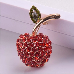 Broche pomme élégante avec strass rouges étincelants et feuille dorée sur présentoir