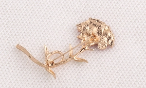 Detailed back view of carnation brooch showing golden metal texture and safety pin clasp