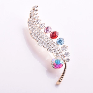 Detailed close-up of a golden feather brooch with colorful crystals and rhinestones