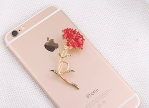 Detailed close-up of a carnation brooch with red rhinestones on a golden base