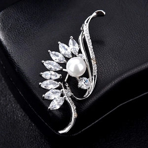Macro shot of silver brooch with large white pearl and marquise-cut zircon feathers