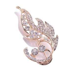 Élégante broche en forme de feuille dorée ornée de strass blancs sur fond blanc