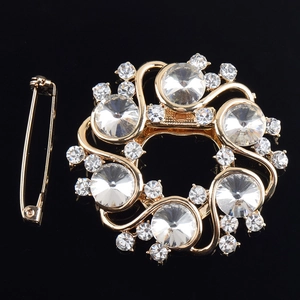 Vue détaillée d'une broche couronne dorée avec cristaux sur une surface noire réfléchissante
