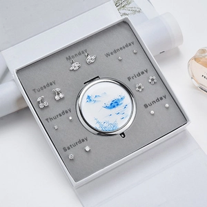 Gros plan d'un coffret de 7 paires de boucles d'oreilles avec un petit miroir de paysage